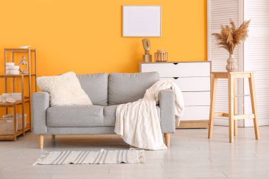 Modern oturma odası. Katlanan ekran, gri kanepe ve çekmeceler.