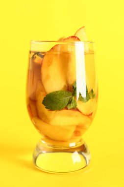 Bir bardak taze şeftalili limonata, sarı arka planda nane şekeri.