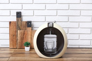 Modern coffee machine with glass of hot espresso on table in kitchen