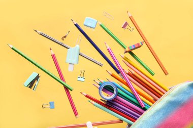Uçan kalem kutusu ve sarı arka planda okul kâğıdı.