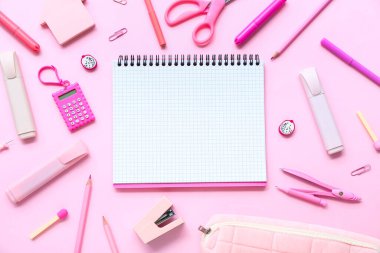 Pembe arka planda farklı kırtasiye malzemesi içeren defter.
