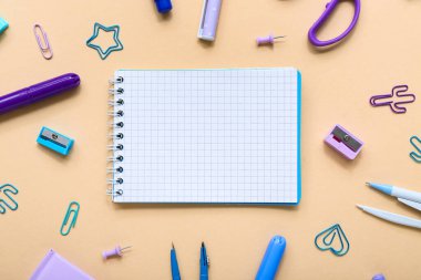 Turuncu arka planda farklı kırtasiye malzemesi içeren defter