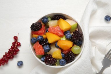 Beyaz ahşap arka planda taze meyve salatası.