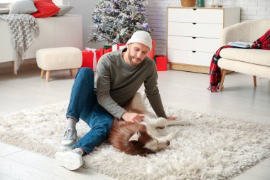 Evde sevimli köpekli yakışıklı bir genç adam.