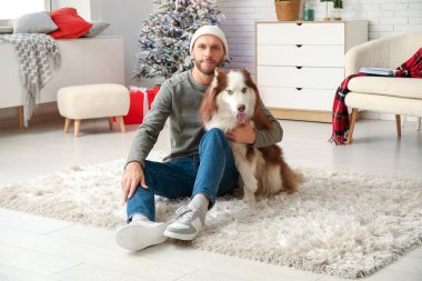 Evde sevimli köpekli yakışıklı bir genç adam.