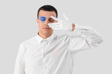 Beyaz arka planda yüzü boyalı genç bir adam.