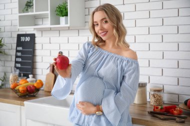 Mutfakta elmalı hamile bir kadın.