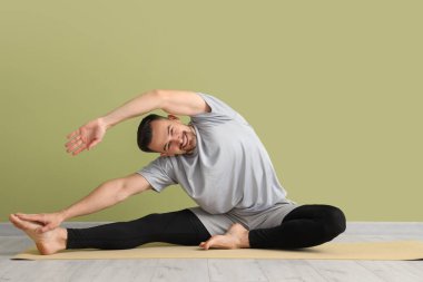 Yakışıklı adam yeşil duvarın yanında yoga yapıyor.