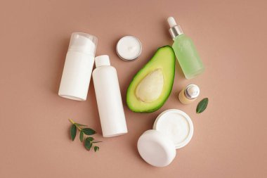 Renk arkaplanına farklı kozmetik ürünleri ve avokado seti