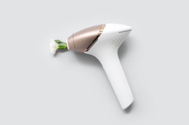 Işık arka planında modern fotoepilatör ve çiçek