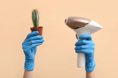 Kaktüslü lastik eldivenli kadın eller ve renkli fotoepilatör, yakın plan.