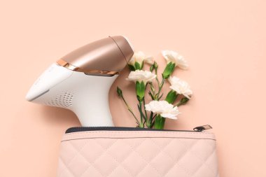 Renkli arka planda modern fotoepilatör ve karanfil çiçeklerine sahip kozmetik çanta, yakın plan