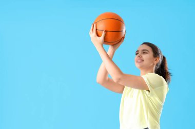 Mavi arka planda topları olan spor kıyafetli genç bir kadın.