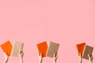 Pembe arka planda kitapları tutan eller