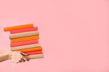 Pembe arka planda kitapları tutan eller