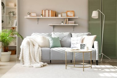 Rahat kanepe, masa ve lamba gri duvarın yanında.