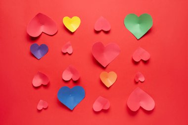 Kırmızı arka planda renkli kağıt kalpler olan kompozisyon. Sevgililer Günü kutlaması