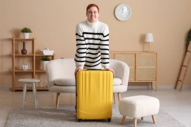 Evinde sarı valizli mutlu genç adam.