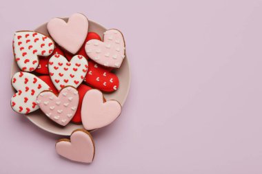 Leylak arka planında kalp şeklinde kurabiyeler olan bir tabak. Sevgililer Günü kutlaması