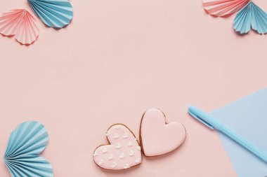 Kağıt kalpli kurabiyeler ve pembe arkaplanlı zarf. Sevgililer Günü kutlaması