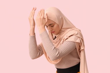 Genç Müslüman kadın pembe arka planda dua ediyor