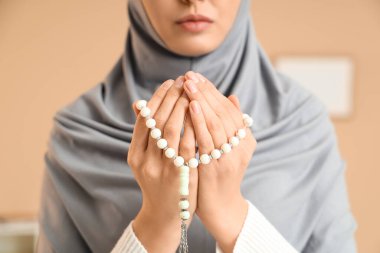 Boncuklu genç Müslüman kadın ofiste dua ediyor, yakın plan.