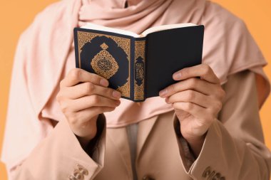 Kuran okuyan genç Müslüman kadın sarı arka planda namaz kılıyor, yakın plan