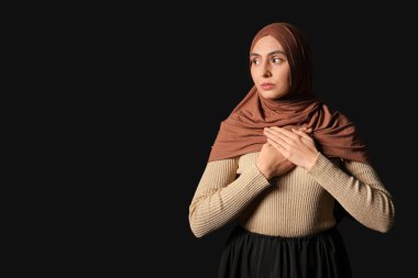 Genç Müslüman kadın siyah arka planda dua ediyor