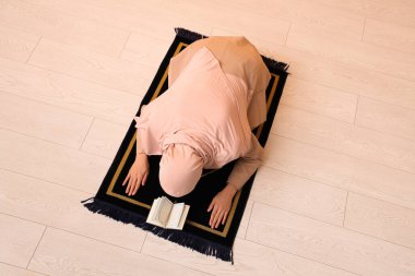 Kuran 'ı dinleyen genç Müslüman kadın evinde dua ediyor.