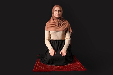 Genç Müslüman kadın siyah arka planda dua ediyor