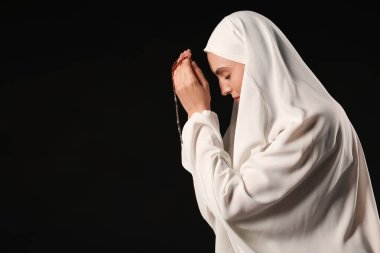 Siyah arka planda dua eden boncuklu genç Müslüman kadın