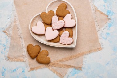 Açık mavi arkaplanda farklı tatlı kalp şekilli kurabiyeler.