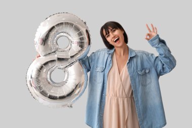 Gri arka planda 8 numaralı figür şeklinde balonu olan güzel genç bir kadın. Uluslararası Kadınlar Günü