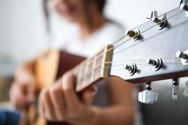 Evde gitar çalan genç bir kadın, yakın plan.