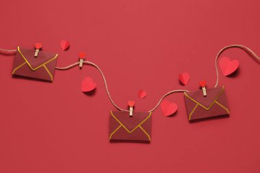 İpte asılı zarflar ve renkli arka planda kağıt kalpler olan kompozisyon. Sevgililer Günü kutlaması