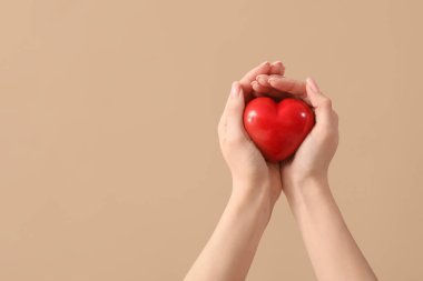 Kahverengi arka planda kalbi olan bir kadın eli. Sevgililer Günü kutlaması