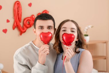 Sevgililer gününde evde kalp şeklinde balonları olan komik genç bir çift.