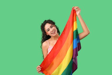 Yeşil arka planda gökkuşağı bayrağı olan genç bir Afro-Amerikalı kadın. LGBT kavramı