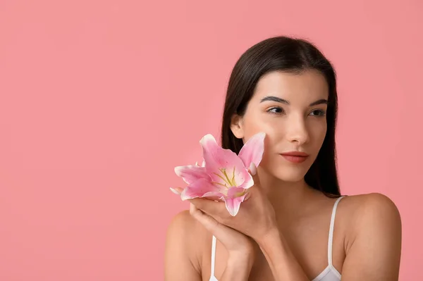 ピンクの背景にユリの花を持つ美しい若い女性 クローズアップ — ストック写真