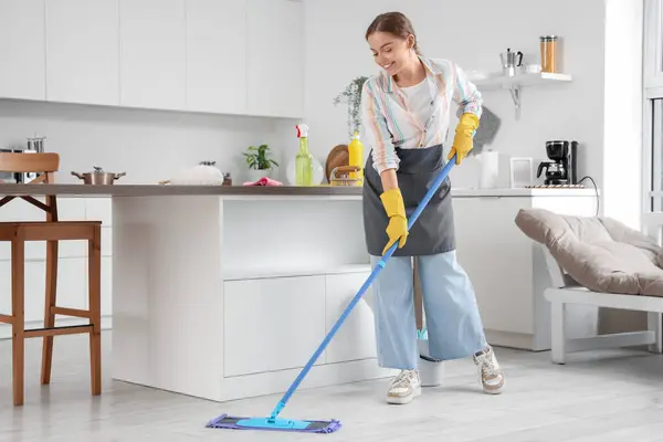 Female janitor mopping floor in kitchen