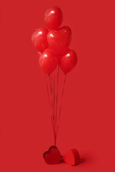 Beautiful heart-shaped balloons and gifts for Valentine's Day celebration on red background
