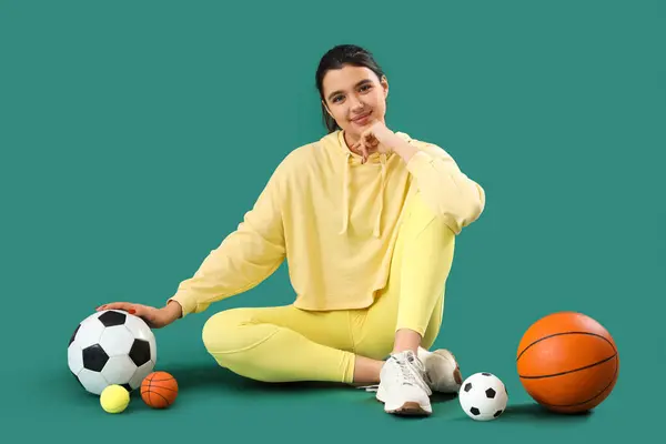 Ung Kvinna Sportkläder Med Bollar Sitter Grön Bakgrund — Stockfoto