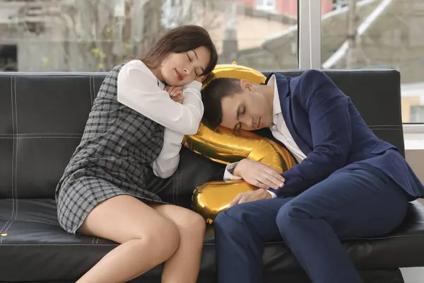 Drunk business colleagues sleeping on couch after New Year party in office