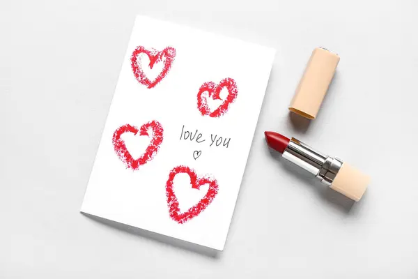 Greeting card with text LOVE YOU and red lipstick on grey background. Valentine\'s Day celebration