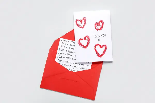 Red envelope and card with text LOVE YOU on grey background. Valentine\'s Day celebration