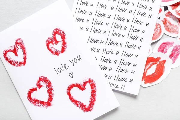 Greeting cards with text I LOVE YOU and lipstick kiss marks on grey background, closeup. Valentine\'s Day celebration