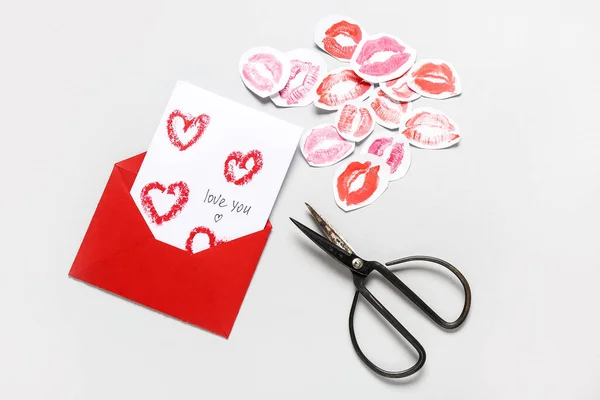 Envelope, card with text LOVE YOU, lipstick kiss marks and scissors on grey background. Valentine\'s Day celebration