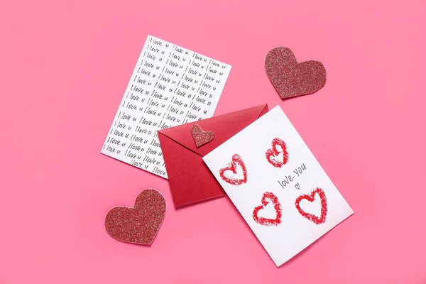 Composition with greeting cards, envelope and hearts on pink background. Valentine's Day celebration