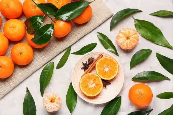 Sweet mandarins with star anise, cinnamon and leaves on grey background