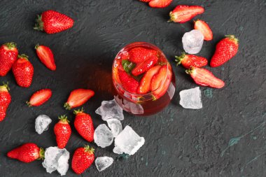 Siyah masada bir bardak lezzetli çilek suyu ve buz.